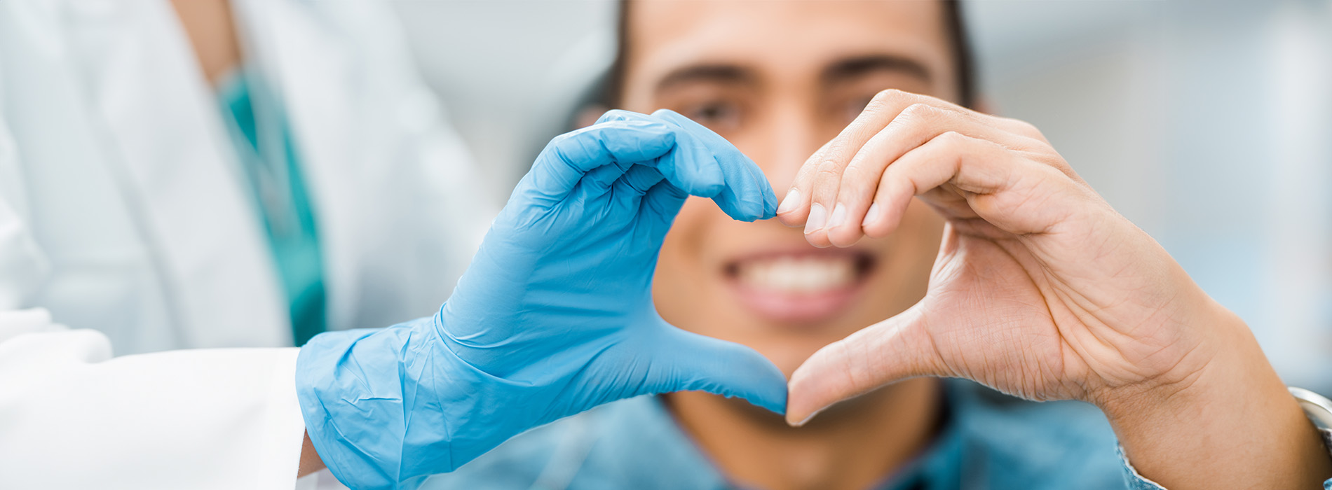 The image shows a group of people, possibly professionals given their attire and the setting that appears to be an office or professional environment. They are gathered around a table with a laptop on it, engaged in what seems to be a discussion or meeting.