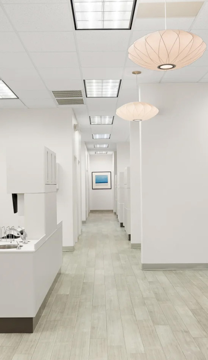 The image shows a modern dental or medical office interior with a dental chair, equipment, and a clean, professional environment.